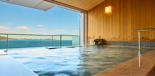 広がる湖の景色を望む、開放的な露天風呂。湯船の湯気と木の壁が温かみを感じさせ、リラックスできる空間。