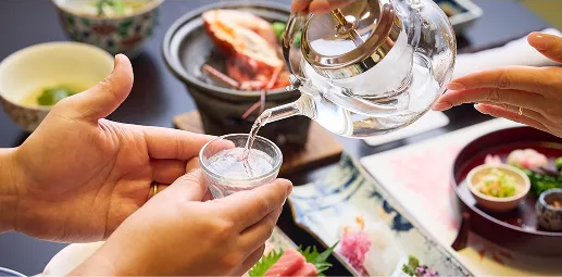 美しく盛り付けられた伊勢海老の刺身または蒸し料理。鮮やかな赤色の伊勢海老と緑色の野菜が、食欲をそそる。