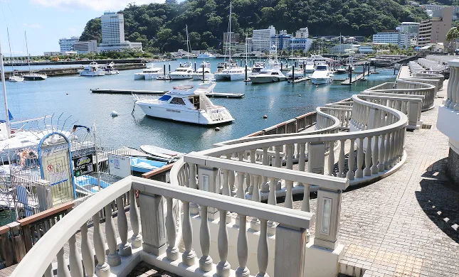多くのボートが停泊する港と、そこを見下ろすように弧を描く白い手すりの遊歩道。